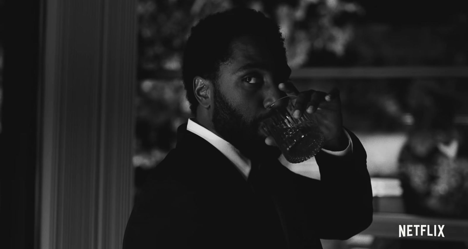 a man in a suit drinking from a glass