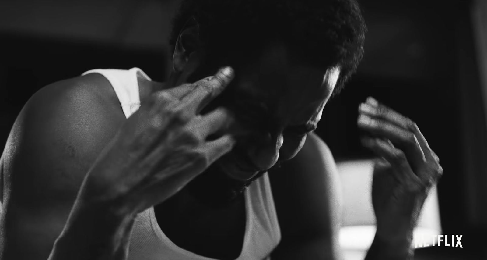 a black and white photo of a man holding his hands to his face