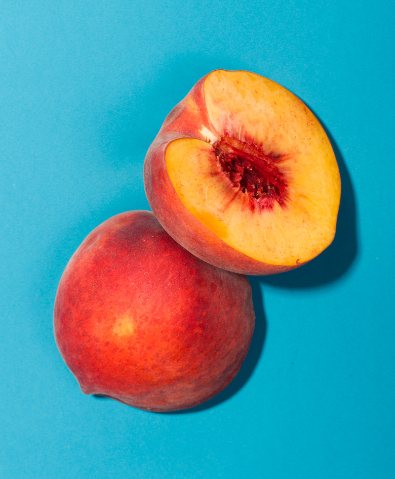 a couple of peaches sitting on top of a blue surface