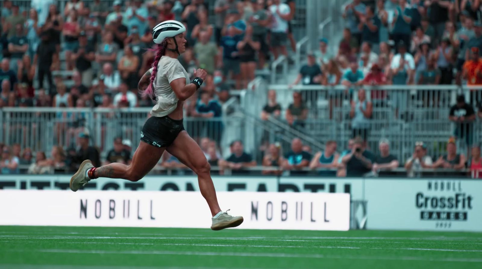 a woman running across a field with a helmet on