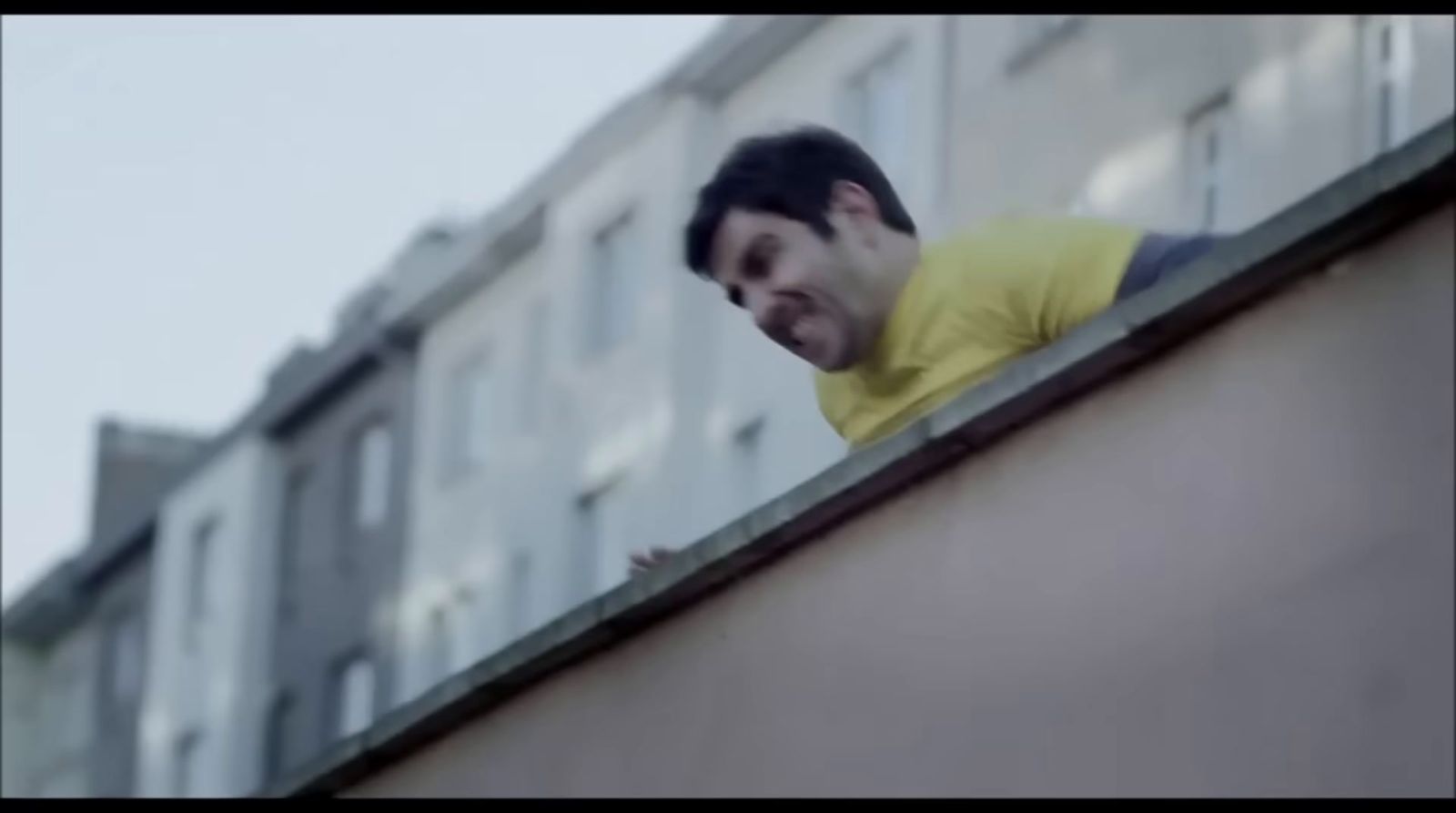 a man standing on top of a roof next to a building