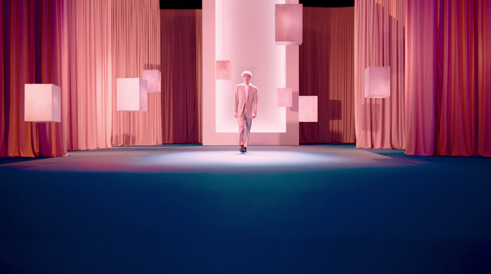 a man standing on a stage in front of red curtains