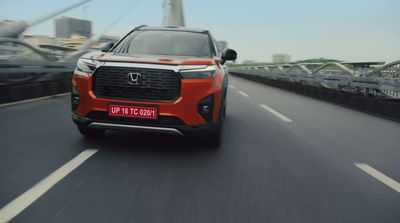 a red suv driving down a highway next to a bridge