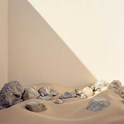 a white wall and some rocks in the sand