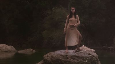 a woman standing on top of a rock next to a river