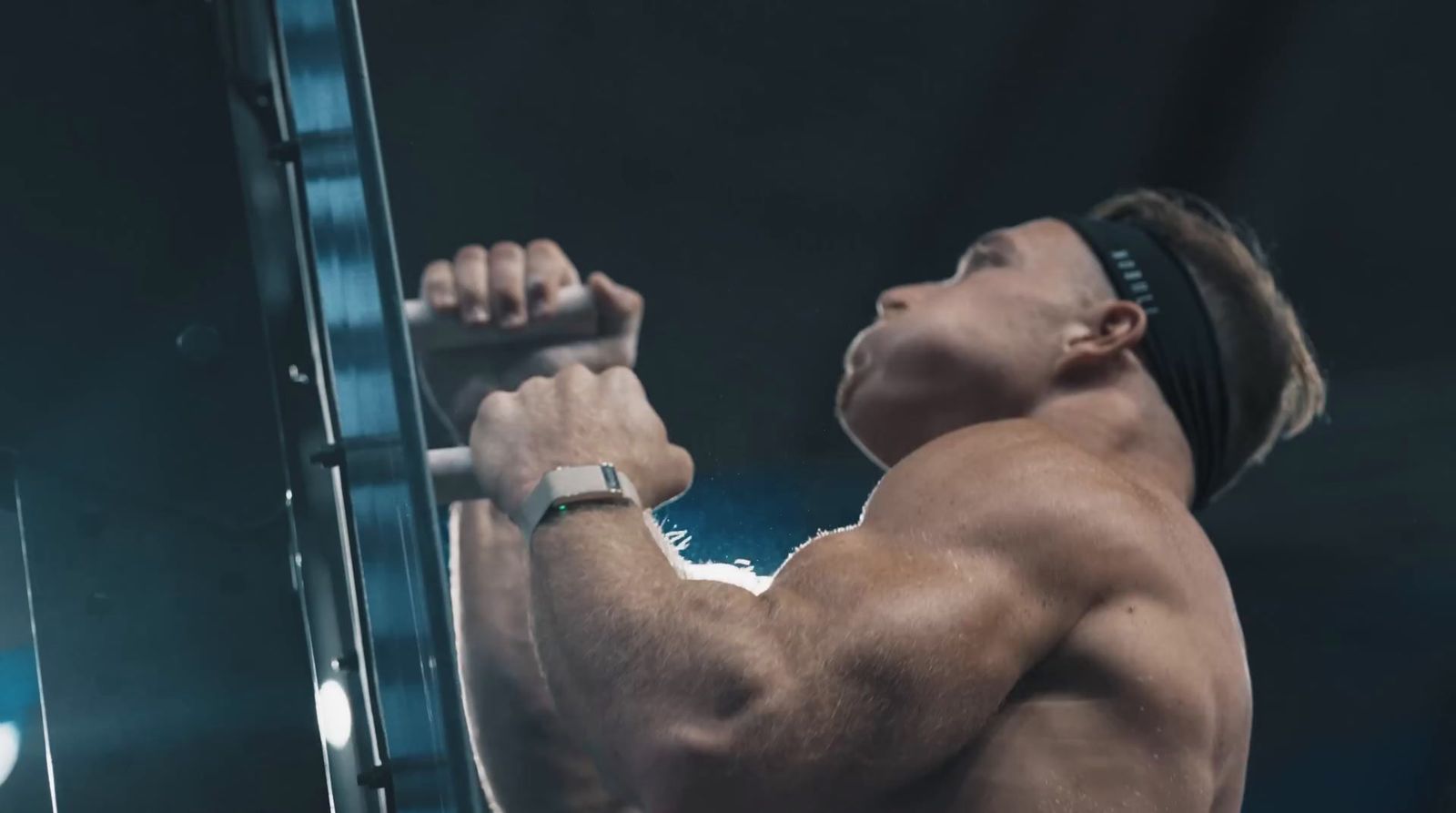 a shirtless man lifting a bar in a gym