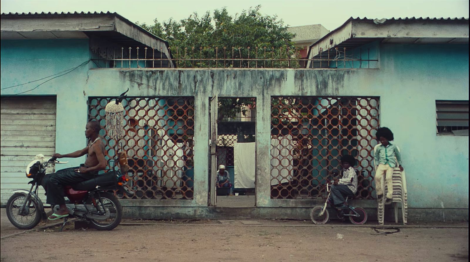 a man riding a motorcycle past a blue building