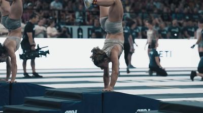 a woman doing a handstand on a beam in front of a crowd