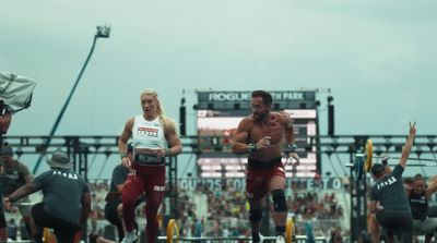 a group of men running on a track in front of a crowd