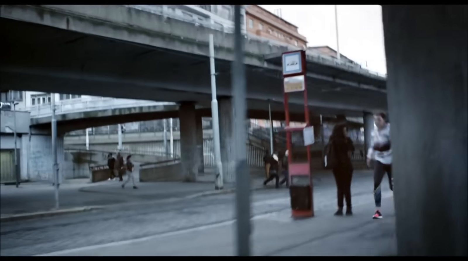 a group of people walking down a street next to a bridge