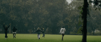 a group of people running across a lush green field