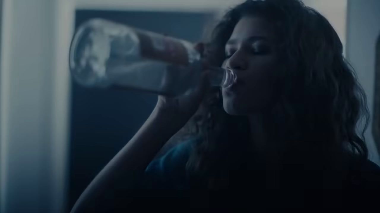 a woman drinking water from a plastic bottle