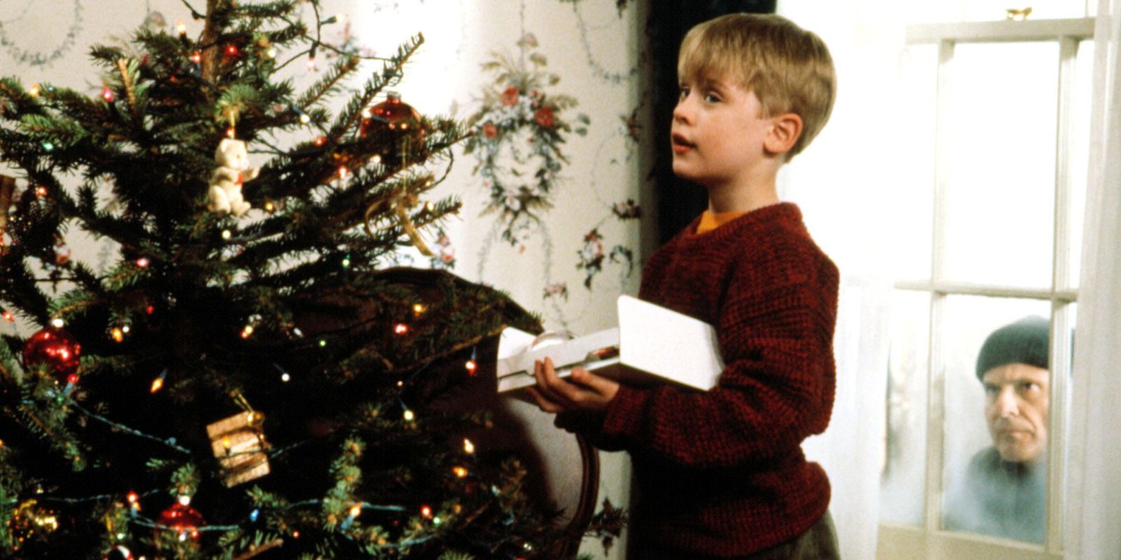 a young boy standing in front of a christmas tree