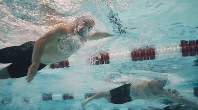 a man swimming in a pool next to another man