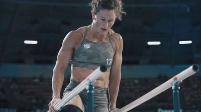 a woman is holding a barbell in a gym