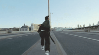 a man walking down a sidewalk with a gun in his hand