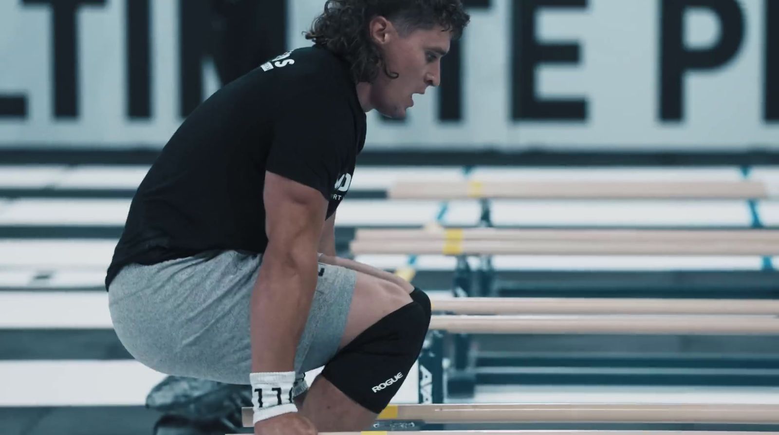 a man squatting on a bench in a gym