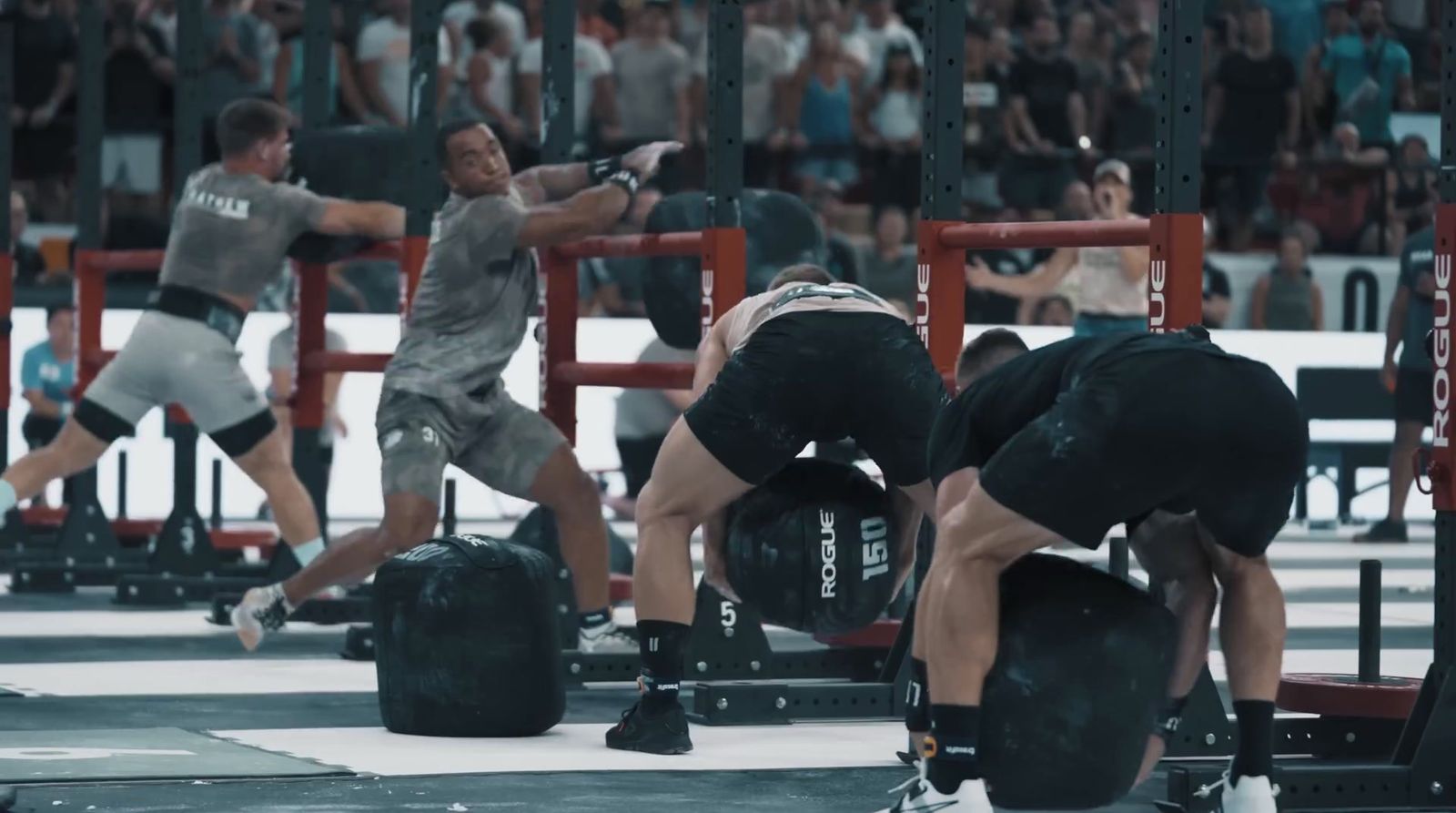 a group of men doing squat exercises in front of a crowd