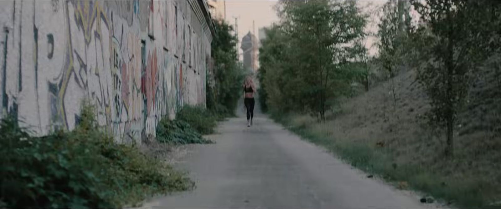 a person walking down a street next to a wall covered in graffiti