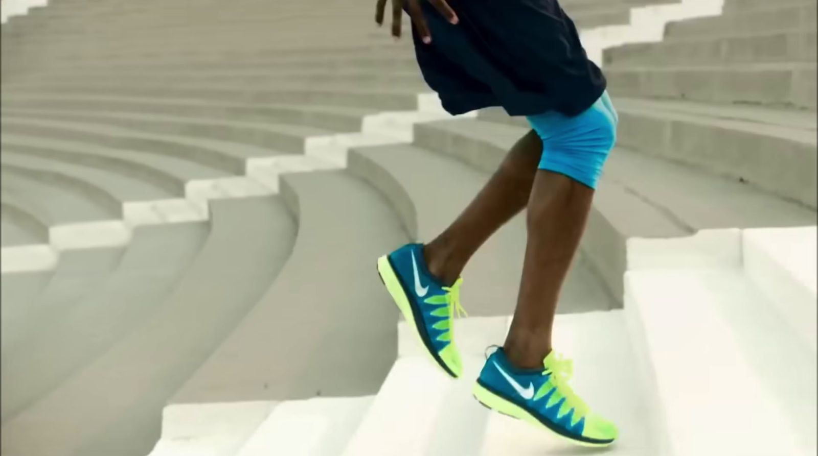 a man in a blue shirt and blue shorts is running up a set of steps