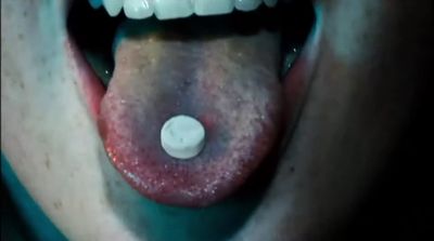 a close up of a person's mouth with a pill in it