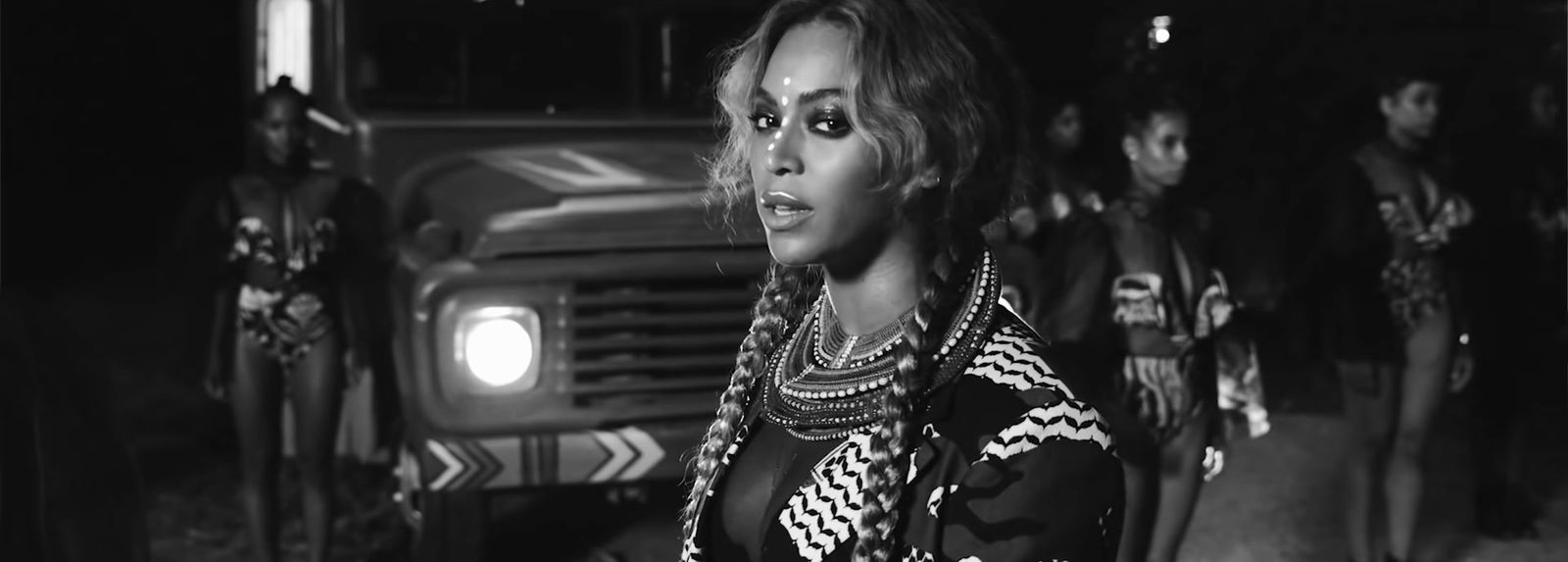 a black and white photo of a woman standing in front of a truck