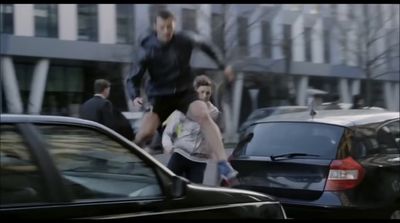 a group of people walking down a street next to parked cars