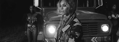 a black and white photo of a woman standing in front of a bus