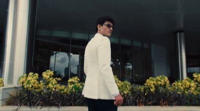 a man in a white suit walking down a sidewalk