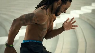 a man with dreadlocks running in a stadium