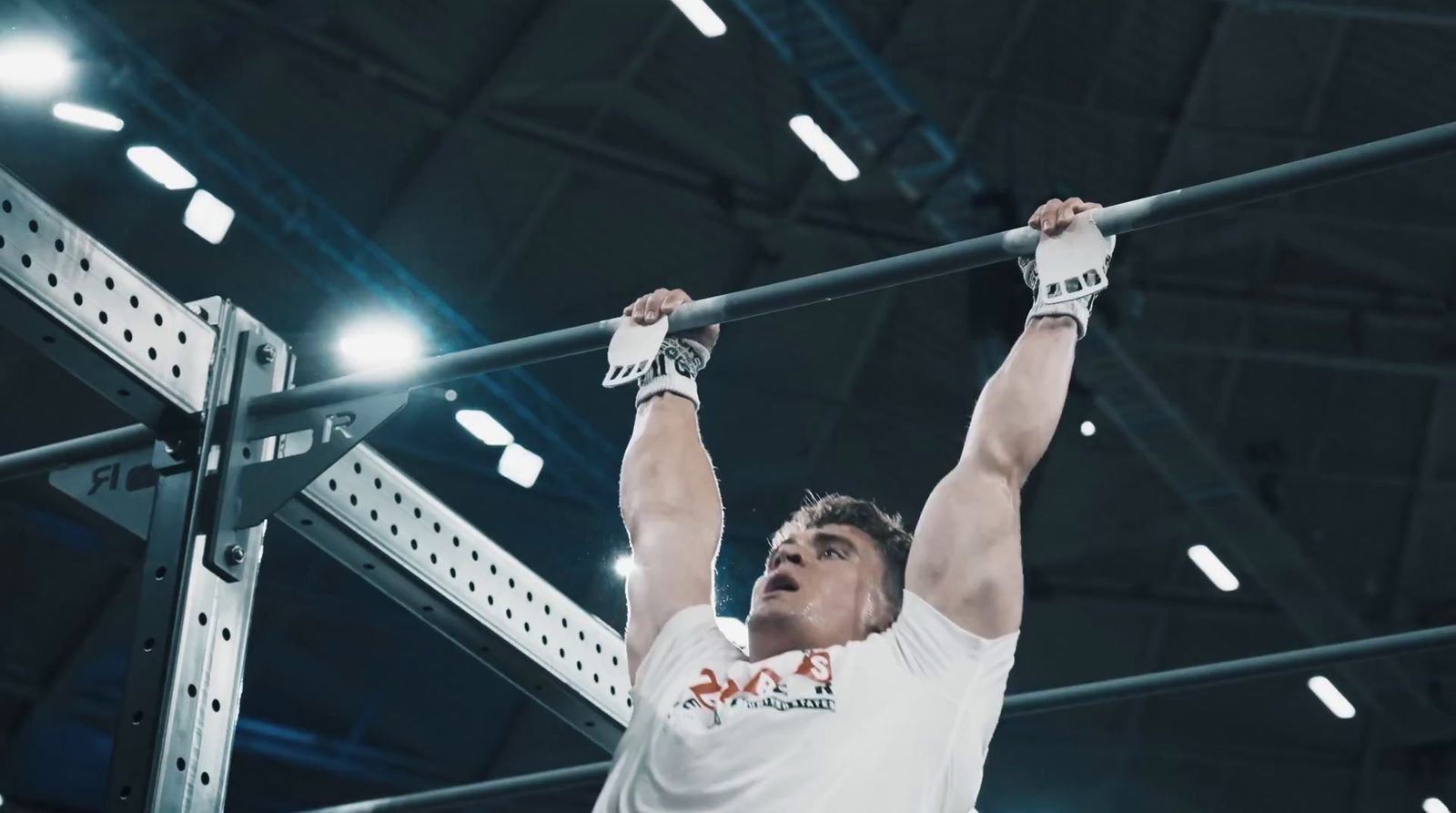 a man in white shirt doing a pull up on a bar