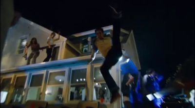 a group of people jumping in the air in front of a house