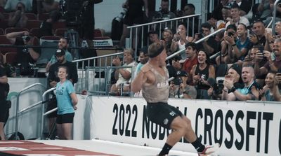 a man running on a track in front of a crowd