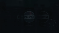 two pepsi cans sitting side by side in the dark