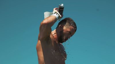 a shirtless man holding a water bottle in the air