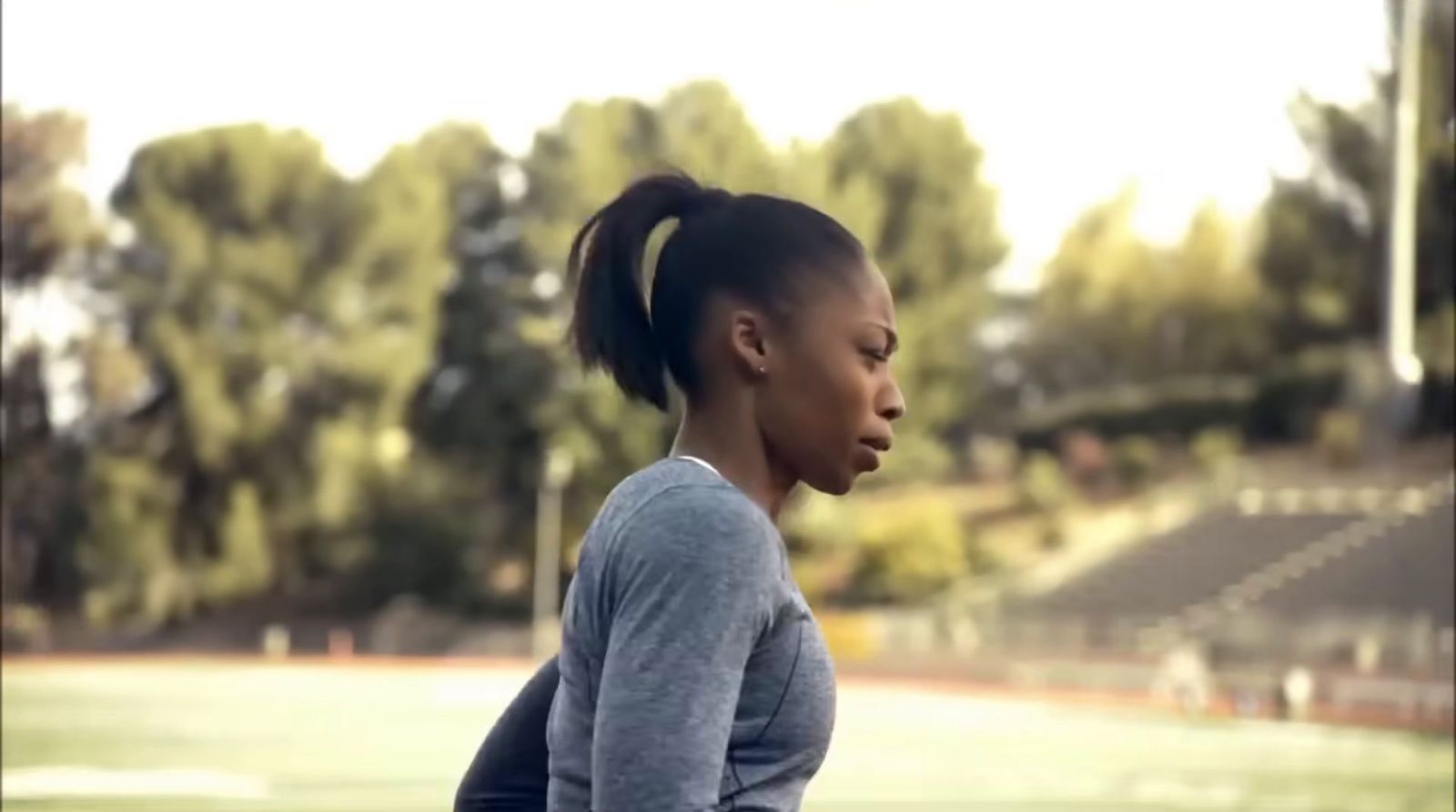 a woman with a ponytail standing in front of a soccer field