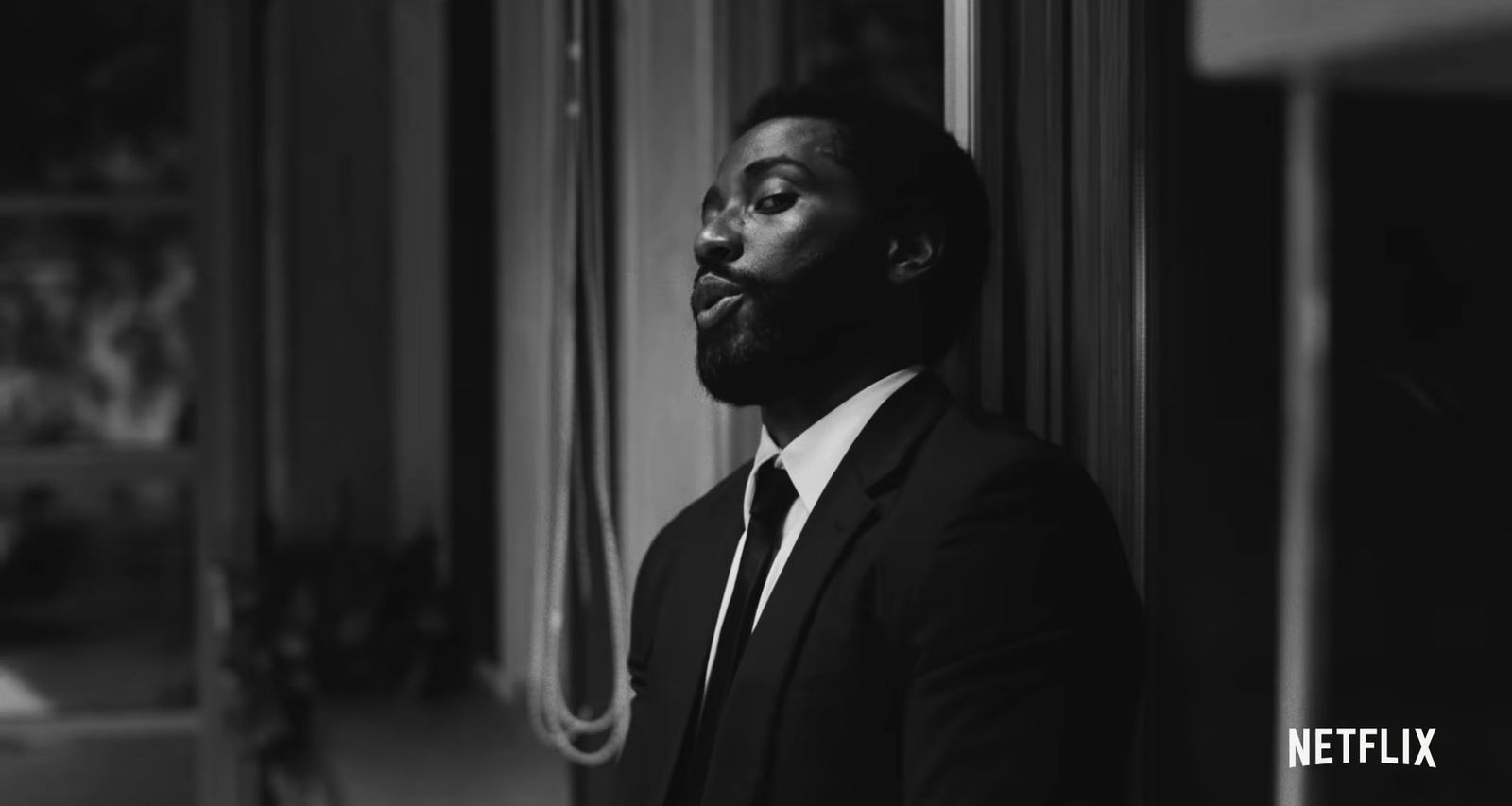 a man in a suit and tie leaning against a wall