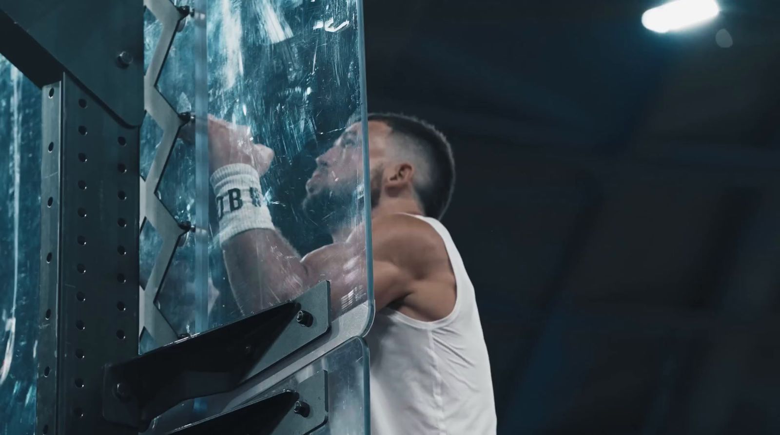 a man in a white tank top working on a machine