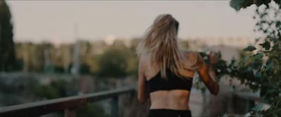 a woman in a black sports bra top walking down a bridge