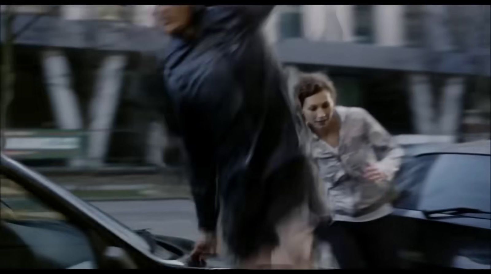 a woman walking down a street next to a car