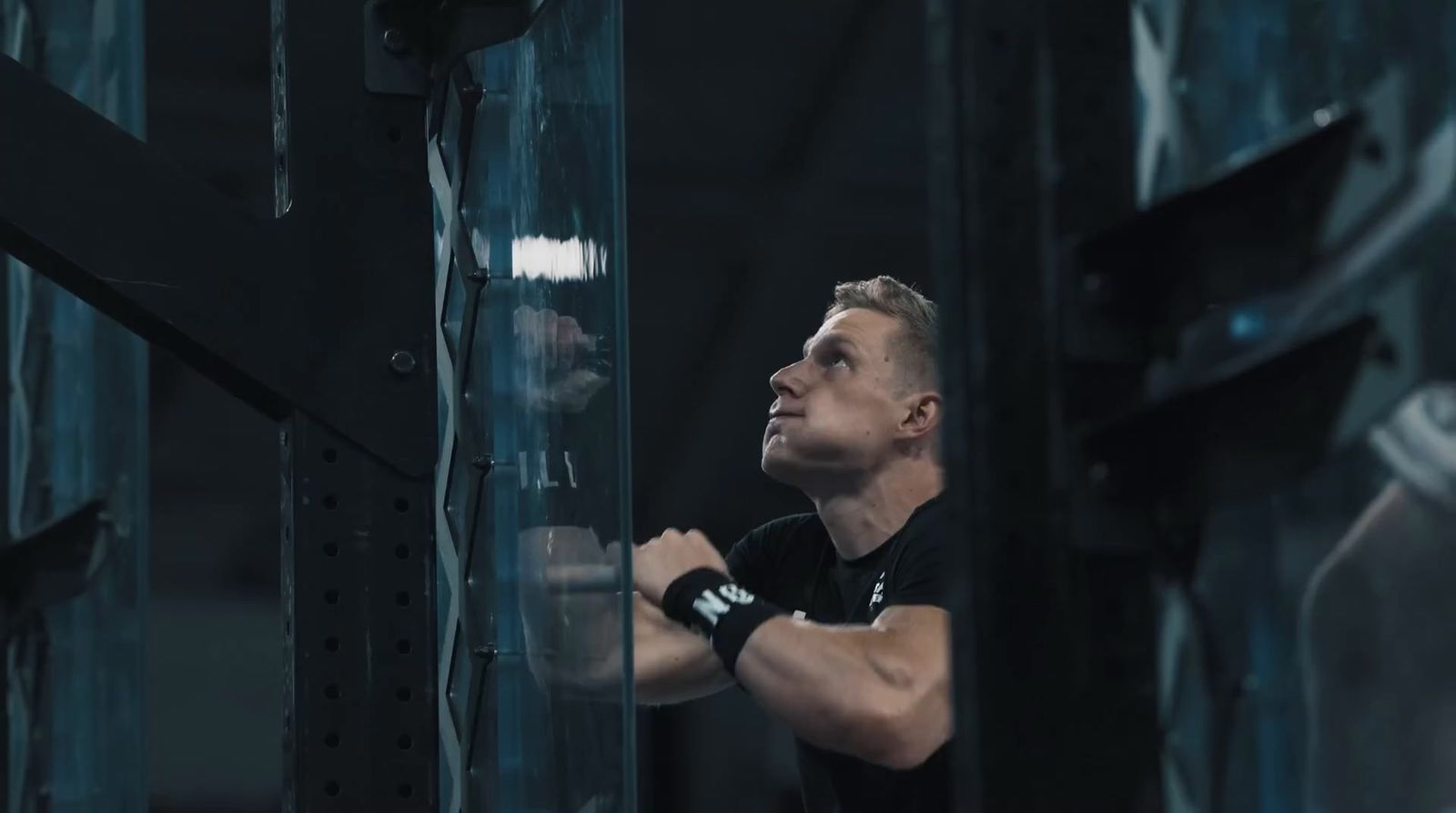 a man in black shirt holding a bar in a gym