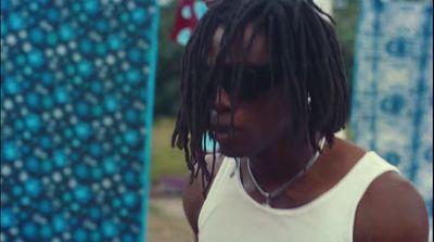 a man with dreadlocks standing next to a surfboard