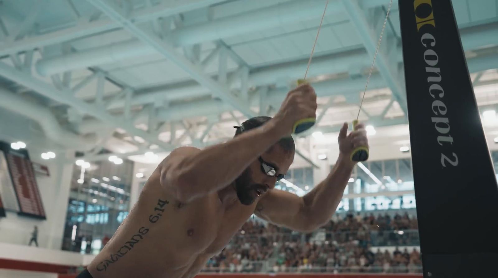 a shirtless man holding a pole in a gym