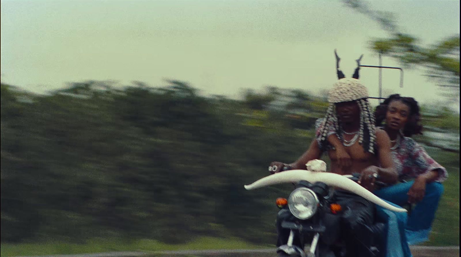 two women riding a motorcycle down a road