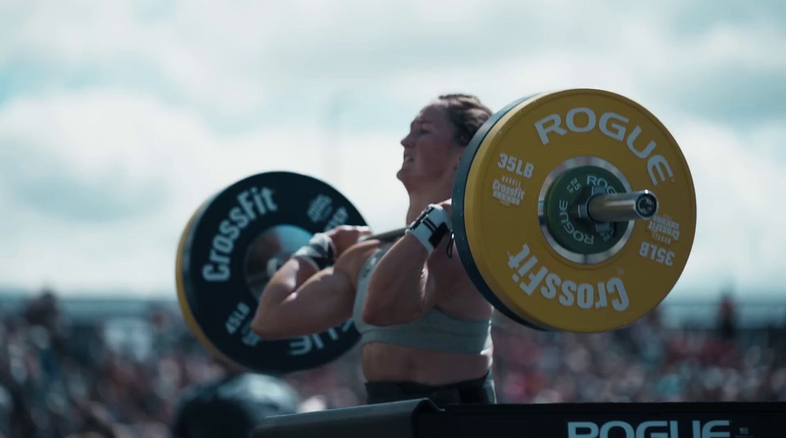 a woman lifting a barbell in front of a crowd