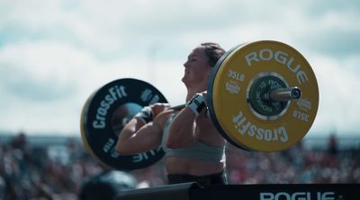 a woman lifting a barbell in front of a crowd