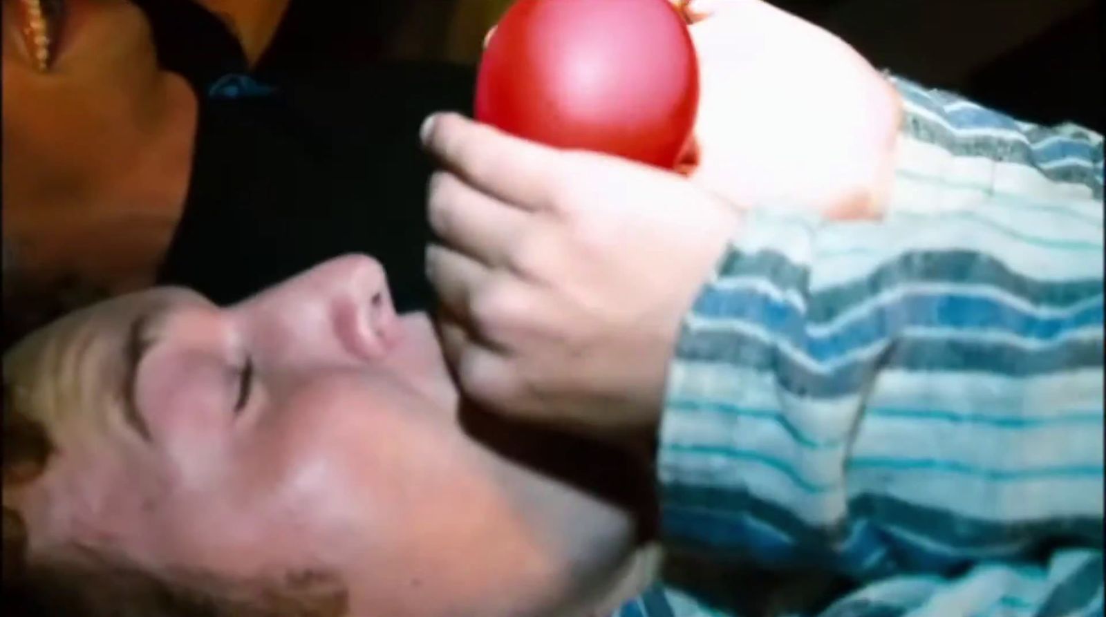 a man holding an apple up to his face