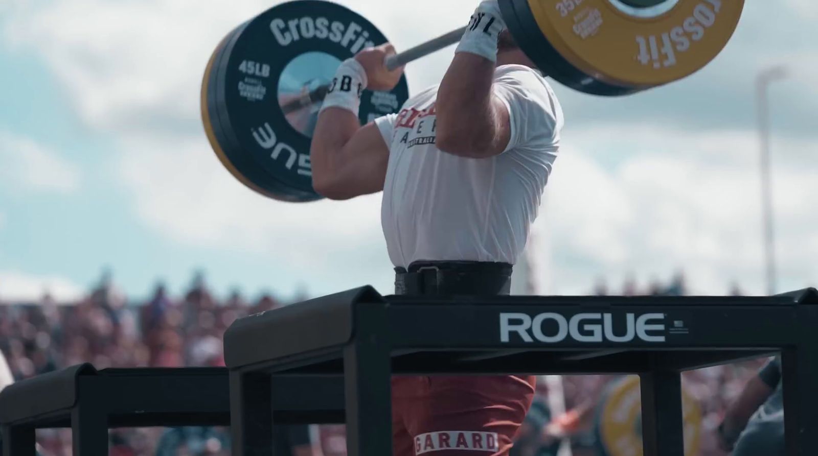 a man holding a barbell in front of a crowd