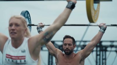 a man and a woman holding up a barbell