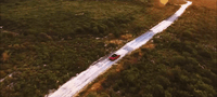 a red car driving down a snow covered road